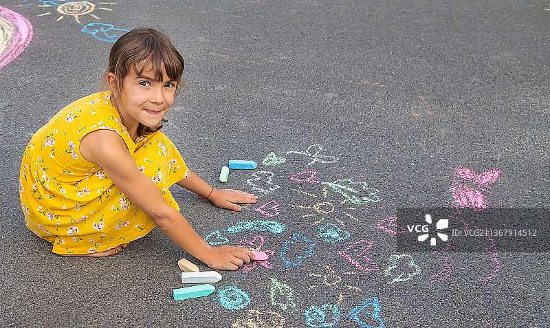 孩子用粉笔在柏油路上画画图片素材