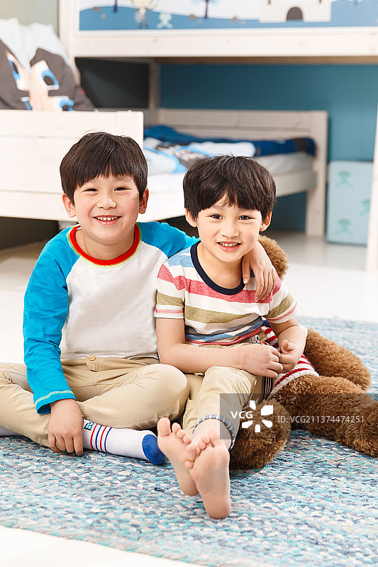 两个男孩坐在卧室的地毯上图片素材