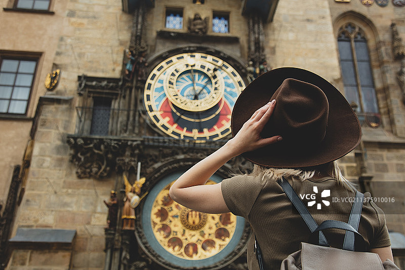 捷克布拉格，一个戴着帽子，背靠着钟的女孩图片素材