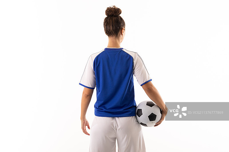 黑白混血的年轻女足球运动员的后视图，足球站在白人背景下图片素材