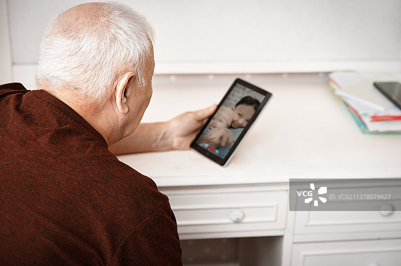 一位老人在平板电脑上与女儿和孙女视频聊天图片素材