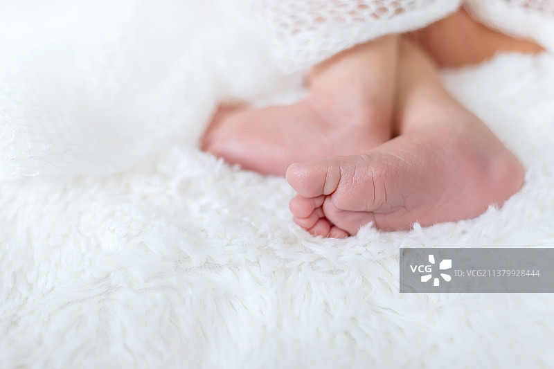 新生儿蹒跚学步的脚在白色背景选择性聚焦图片素材