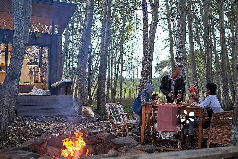 一家人在屋外的树林里享受火炉边的晚餐图片素材
