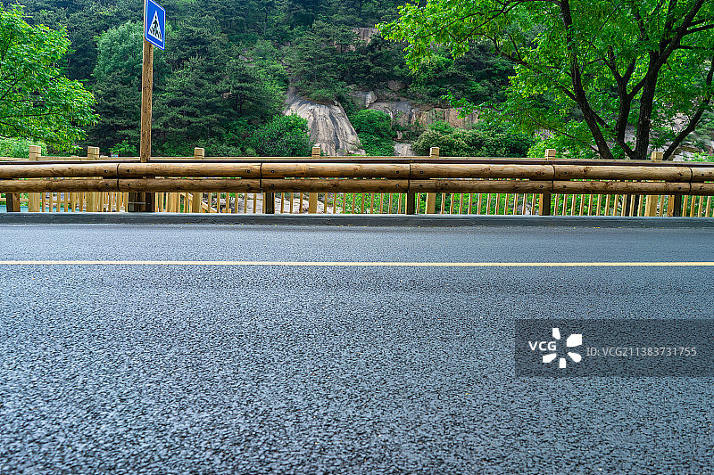 中国非都市风光拍摄主题，山东省泰安市岱岳区彩石溪景区，绿色的山脉，褐色的栏杆，侧面视角拍摄环山路图片素材