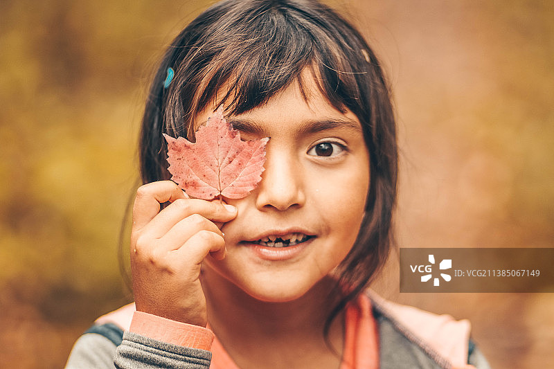 可爱的小女孩带着一片秋天的叶子图片素材