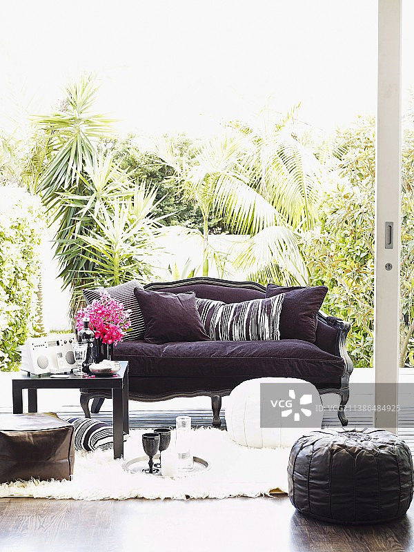 有紫色罩、坐垫和地垫的沙发;饮料在黑色咖啡桌上白色弗洛卡蒂地毯图片素材
