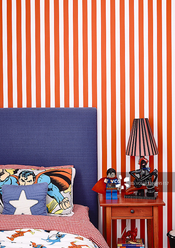 床与漫画床单和床头柜前的条纹墙纸在男孩的房间图片素材