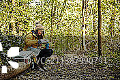 独自秋行，英国，坐在树干上的女人从保温瓶倒饮料在林地图片素材