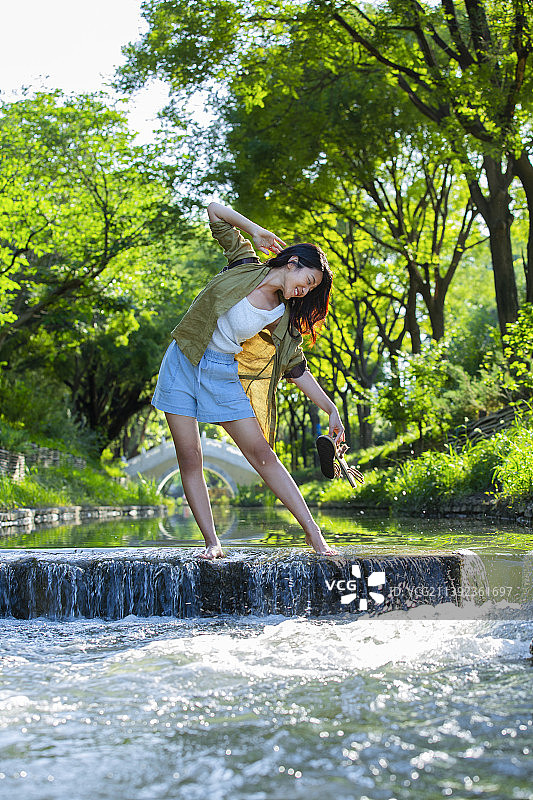年轻女孩在公园小河里跳舞，享受大自然图片素材
