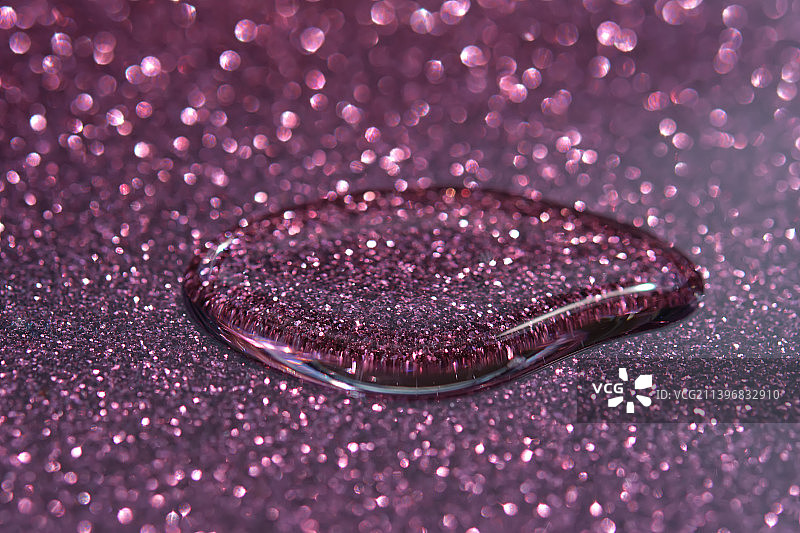 一滴化妆品或香水在闪亮的紫色背景上图片素材