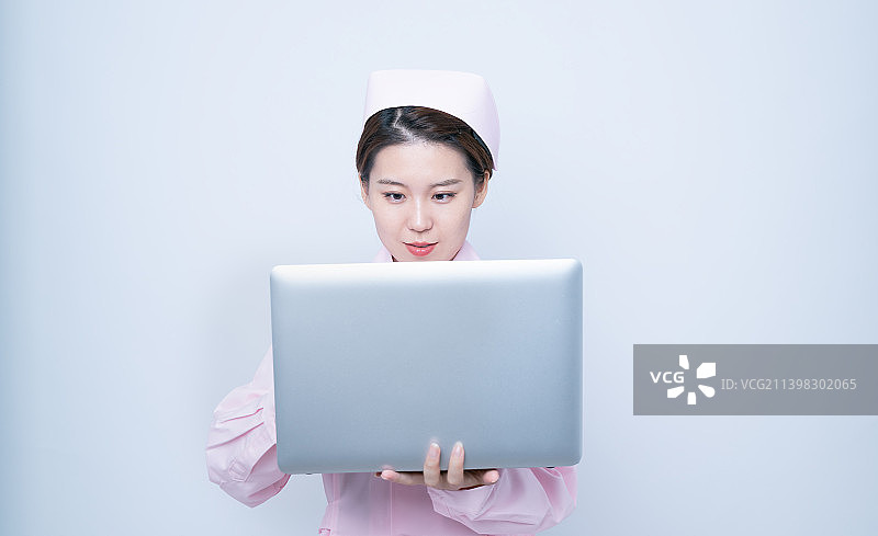 白背景里穿护士服使用笔记本电脑的女护士图片素材
