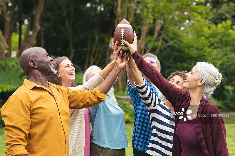 快乐的多种族活跃的高级男性和女性朋友在后院举行橄榄球图片素材