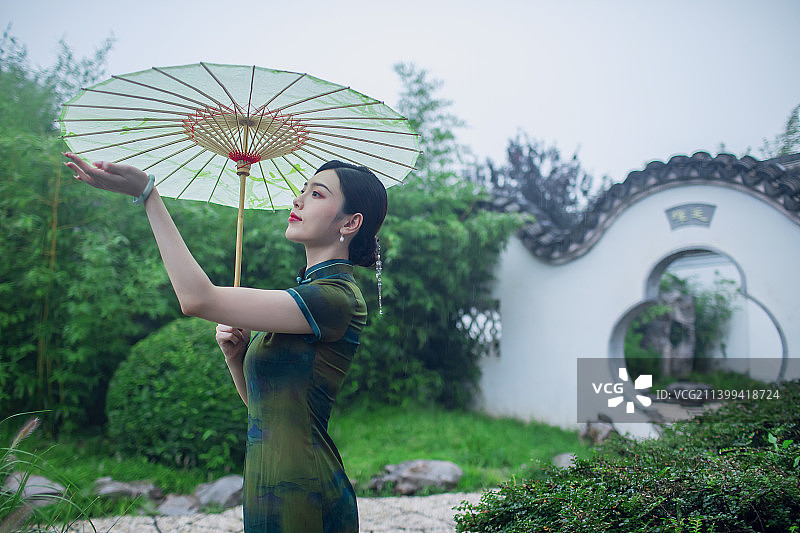 一个东方旗袍美女在中式园林中赏雨图片素材
