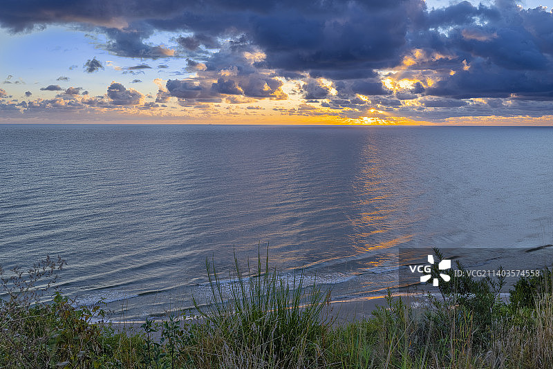 波罗的海海滩上的日出多云的天气，小浪，没有人阳光和水反射，波兰图片素材