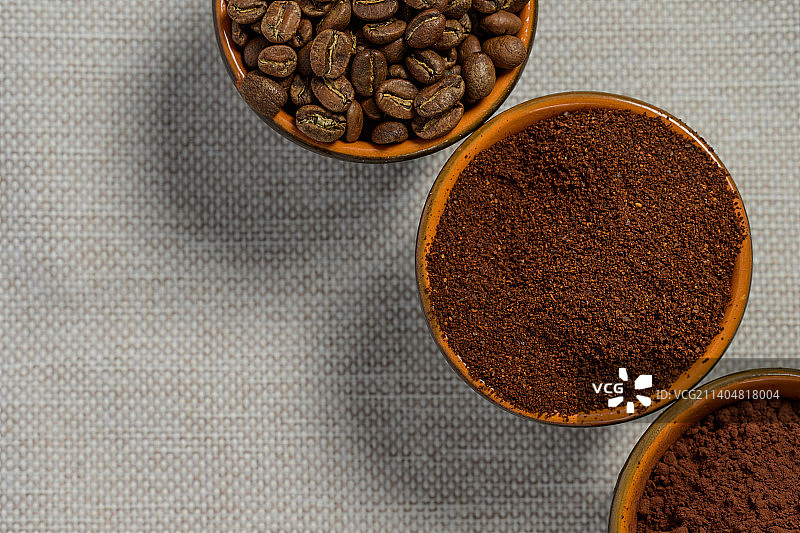 咖啡豆，磨碎的咖啡放在杯子里，亚麻布做背景图片素材