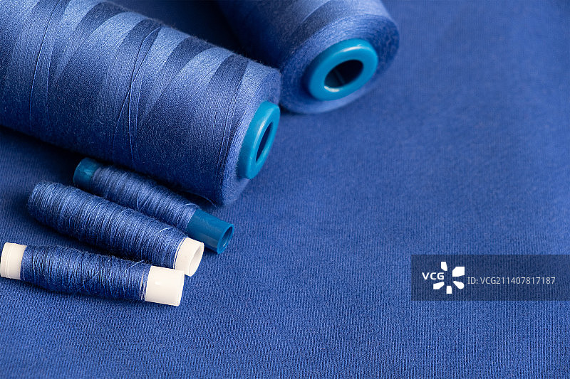 质地的蓝色线在线轴上缝制在一个普通的蓝色背景缝纫材料图案图片素材