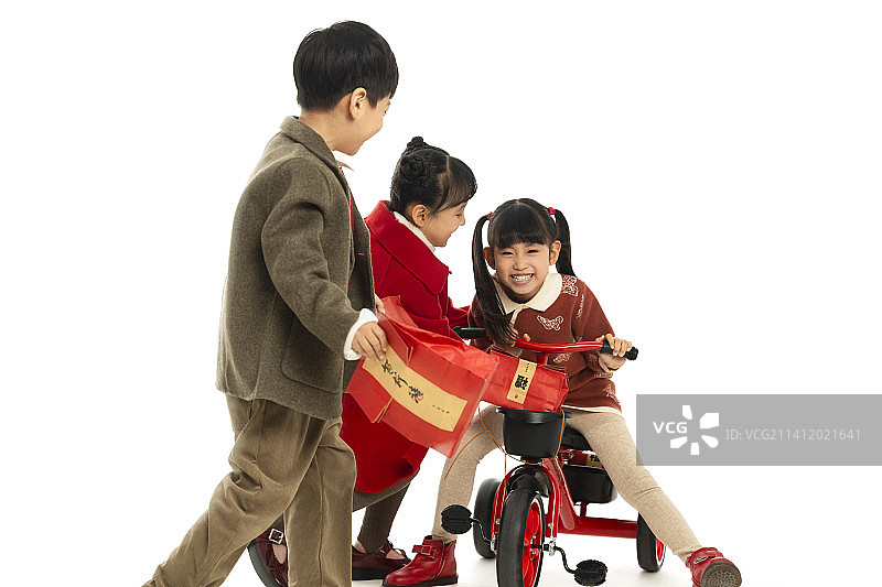 儿童庆祝春节系列：小女孩和小男孩们骑着小三轮车、拿着春节礼物打闹嬉戏图片素材
