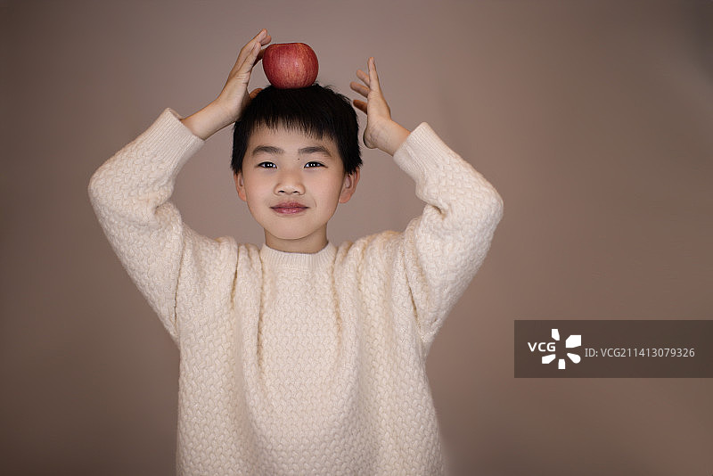 一个帅气的中国小男孩头顶着苹果图片素材