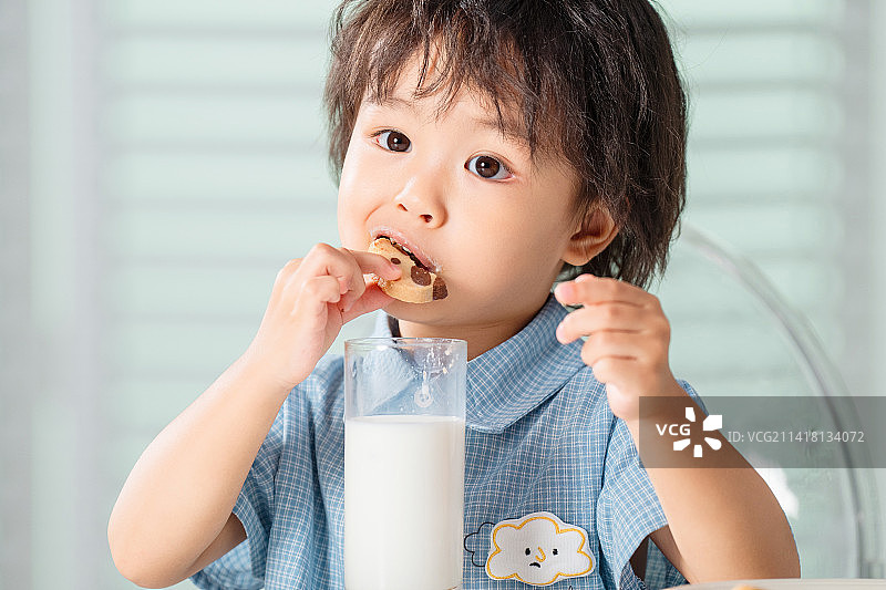 可爱的小男孩吃饼干喝牛奶图片素材