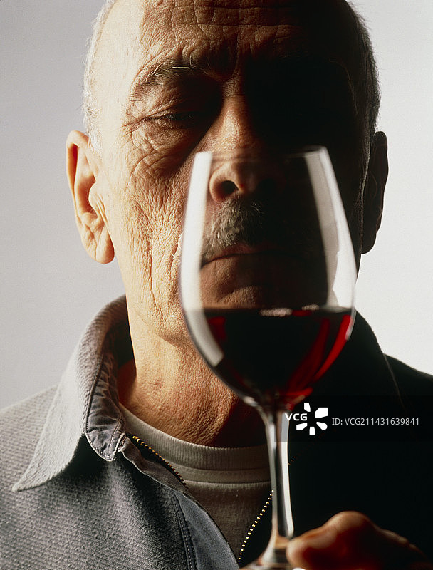一位老人端详着一杯红酒图片素材