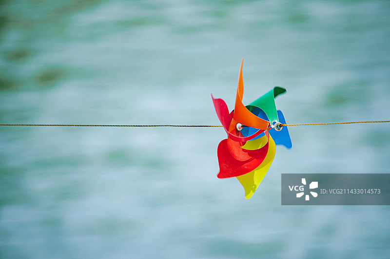 中国休闲娱乐设备用品拍摄主题，线绳上拴着一个彩色的纸质风车，户外白昼无人图像摄影图片素材