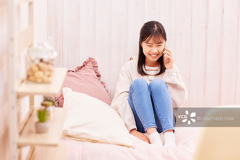 日本女孩在床上玩智能手机图片素材