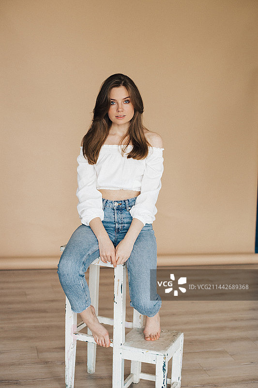 俄罗斯，一个小女孩坐在照相馆的白色高脚椅上图片素材