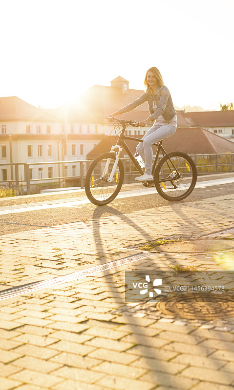 年轻女子在城市里骑自行车图片素材