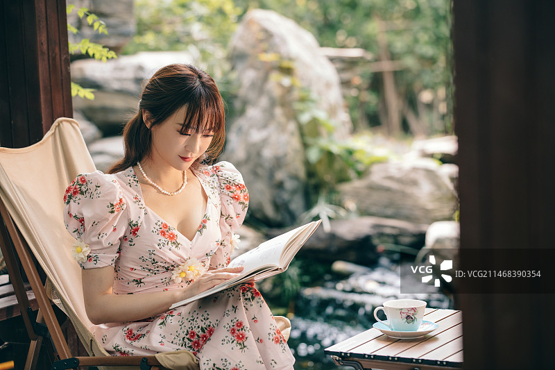青年美女坐在庭院里看书图片素材