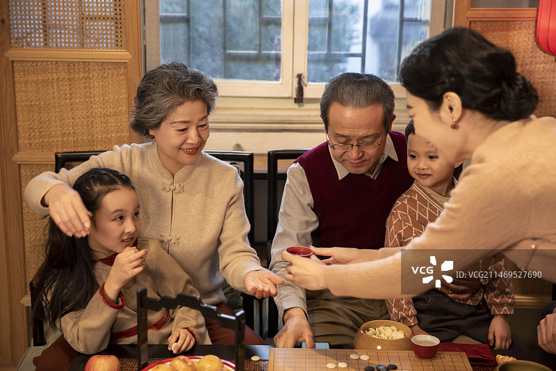 东方家庭过年：幸福一家人在客厅喝茶、聊天、玩围棋图片素材