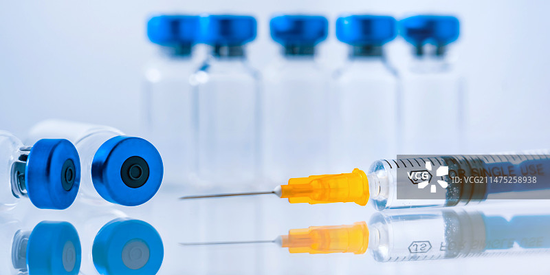 蓝色背景下的新冠疫苗瓶和注射器图片素材