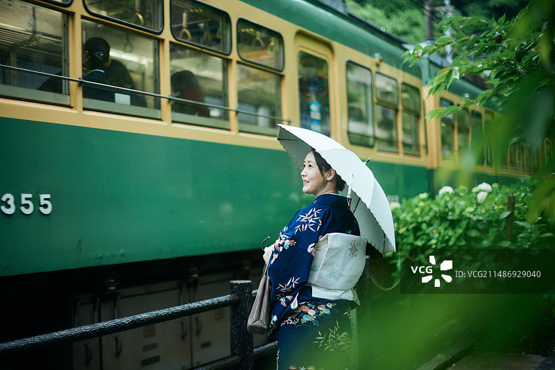一个穿着和服的女人站在火车旁边图片素材