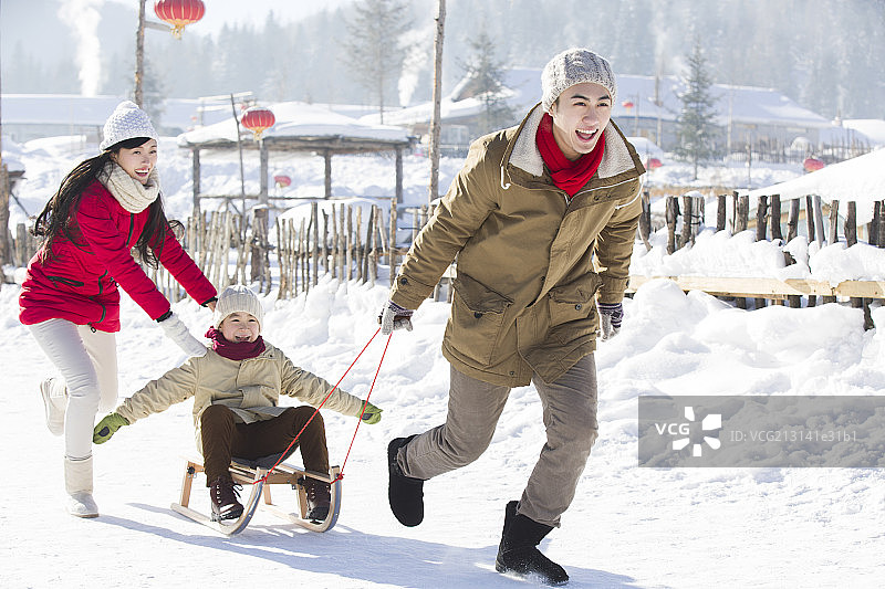 快乐的一家人在雪地上玩雪橇图片素材
