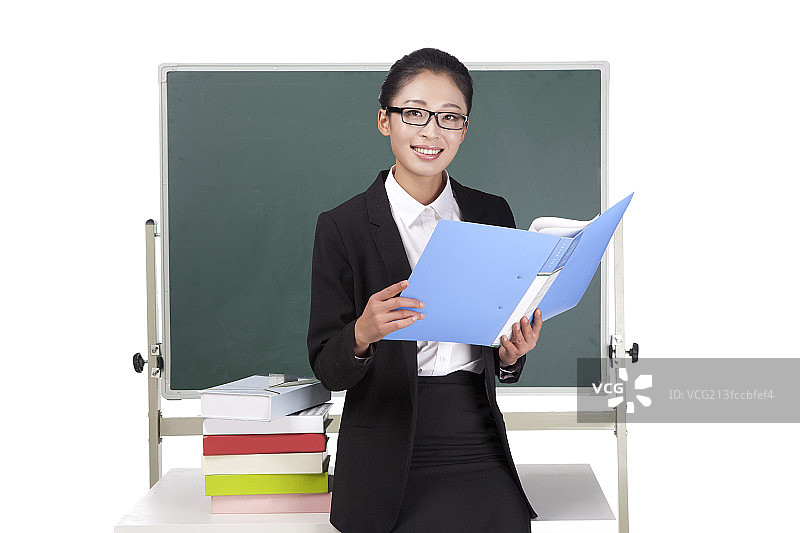 一个青年女教师坐在黑板前备课图片素材