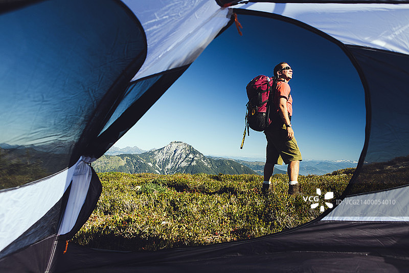 从帐篷里的男人徒步穿越国家森林土地与贝克山在远处的风景。图片素材
