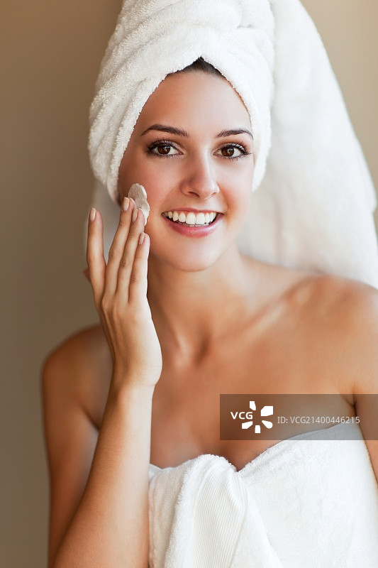一张年轻漂亮的女人在脸上涂护肤霜的照片图片素材