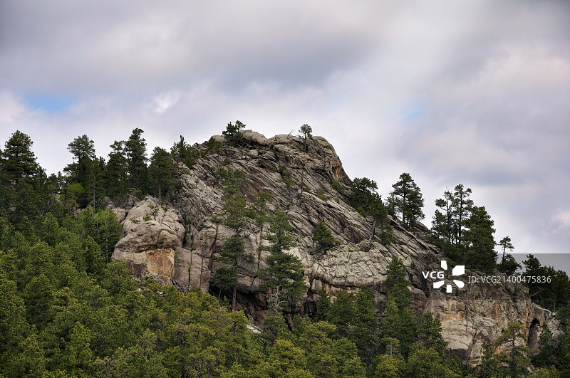 岩石和森林映衬着阴雨的天空图片素材