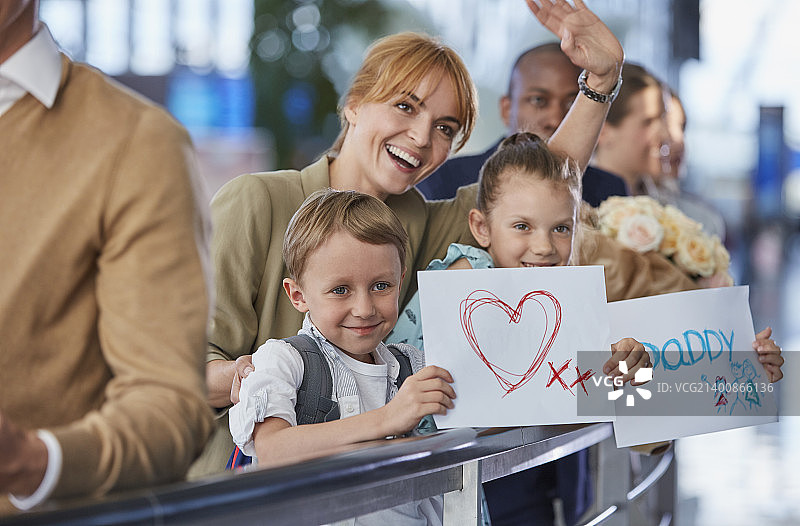 母亲和孩子们在机场举着欢迎父亲的牌子图片素材