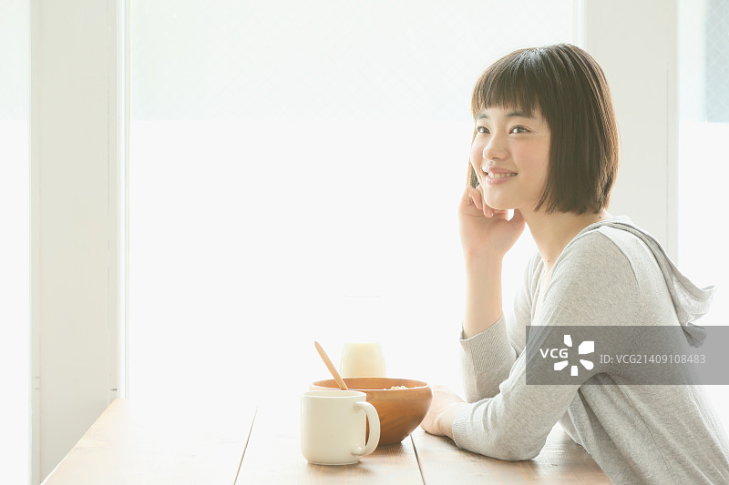 年轻的日本妇女在通风的房间里吃早餐图片素材