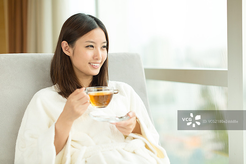 年轻女孩在窗前喝茶图片素材