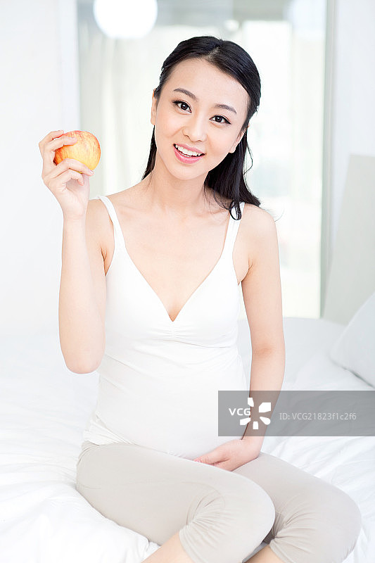 坐在床上拿苹果的孕妇图片素材