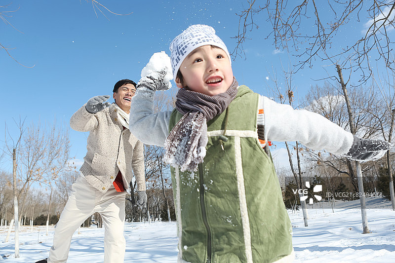 父亲和儿子在雪地上打雪仗图片素材