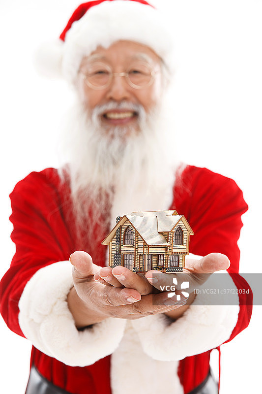 穿着圣诞服的老年人手捧着房屋模型图片素材