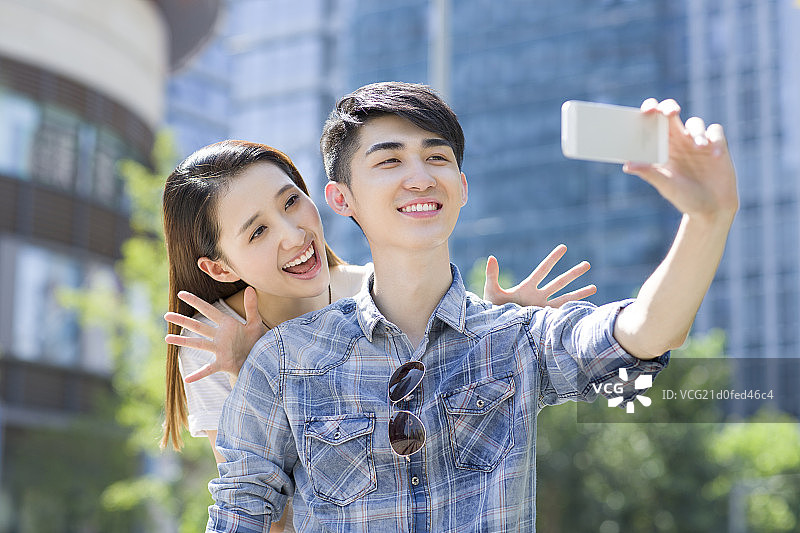 快乐的年轻情侣用手机自拍图片素材
