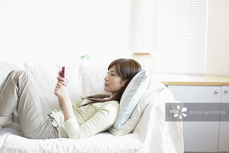 一个女人拿着手机躺在沙发上图片素材