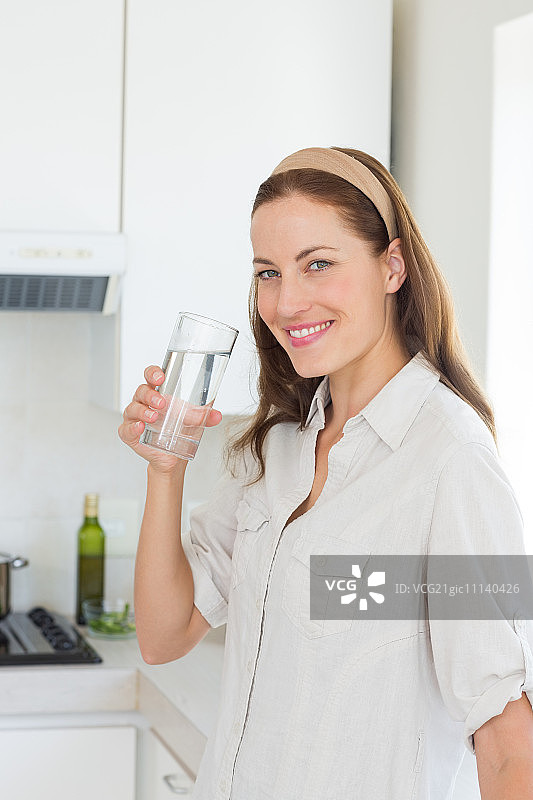 一个年轻女人在厨房喝水的肖像图片素材