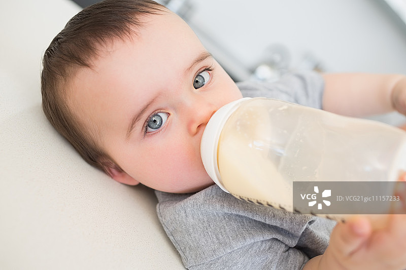 高角度的肖像，天真的婴儿喝牛奶，而躺在厨房柜台图片素材