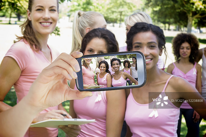 手持智能手机显示乳腺癌活动家照片的合成图像图片素材