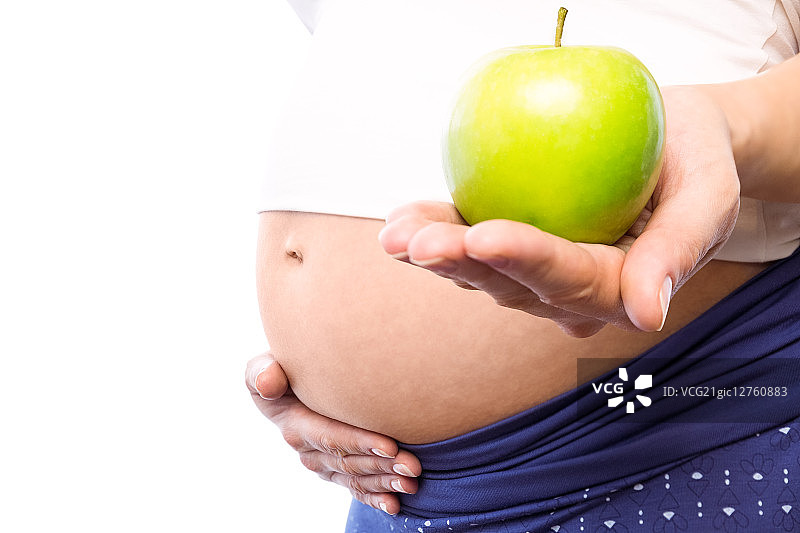 一名孕妇在白底上拿着绿苹果图片素材