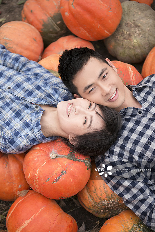 Young couple lying on pile of pumpkins图片素材